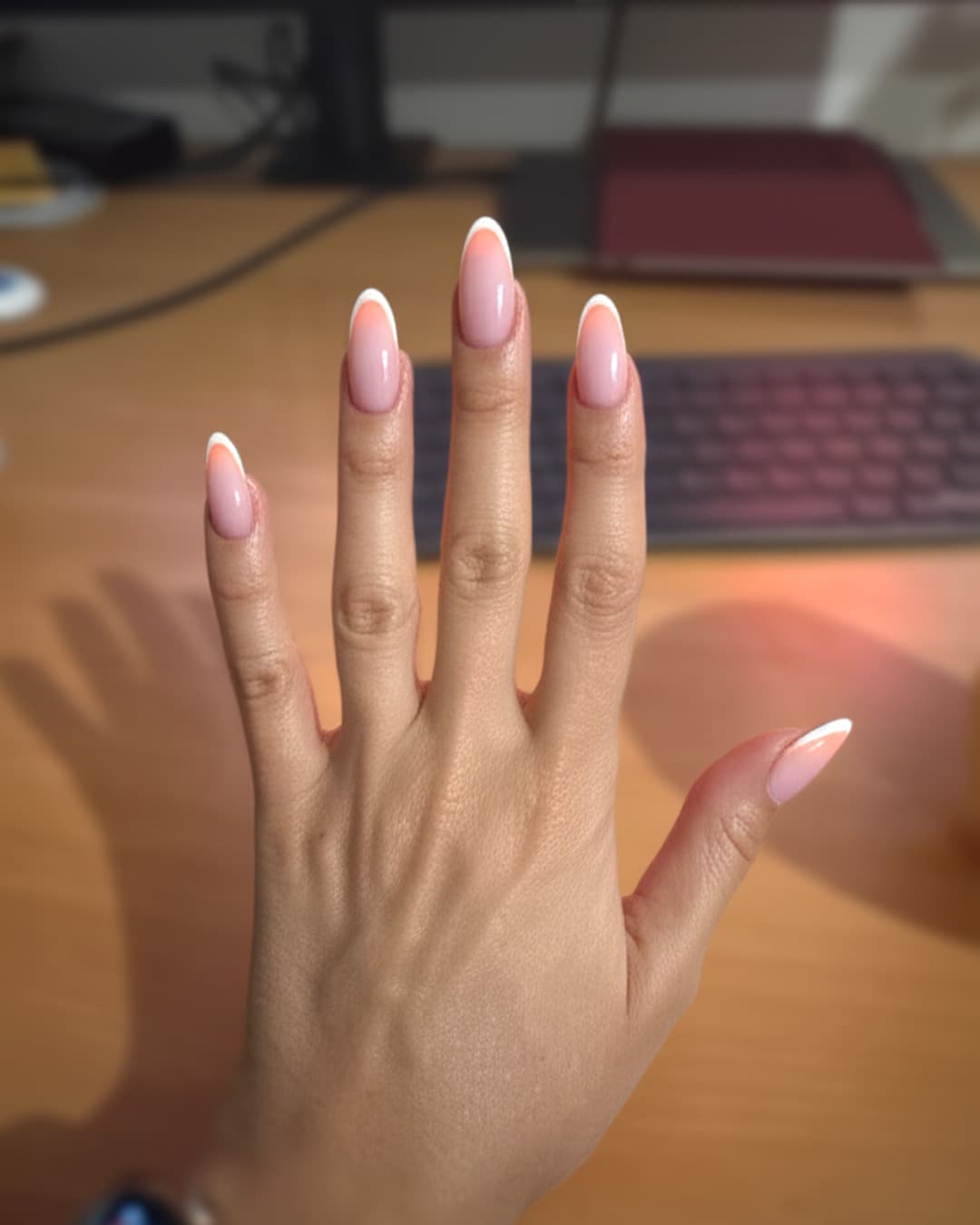 Micro French tips on long almond nails with a sheer nude base